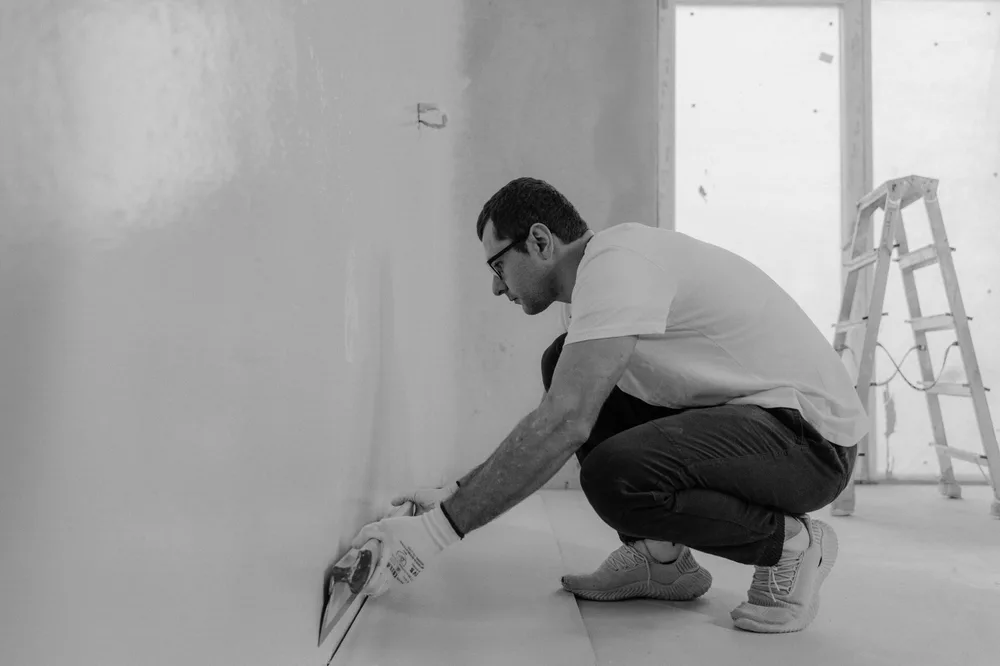 Handwerker bei sorgfältigen Spachtelarbeiten an einer Innenwand